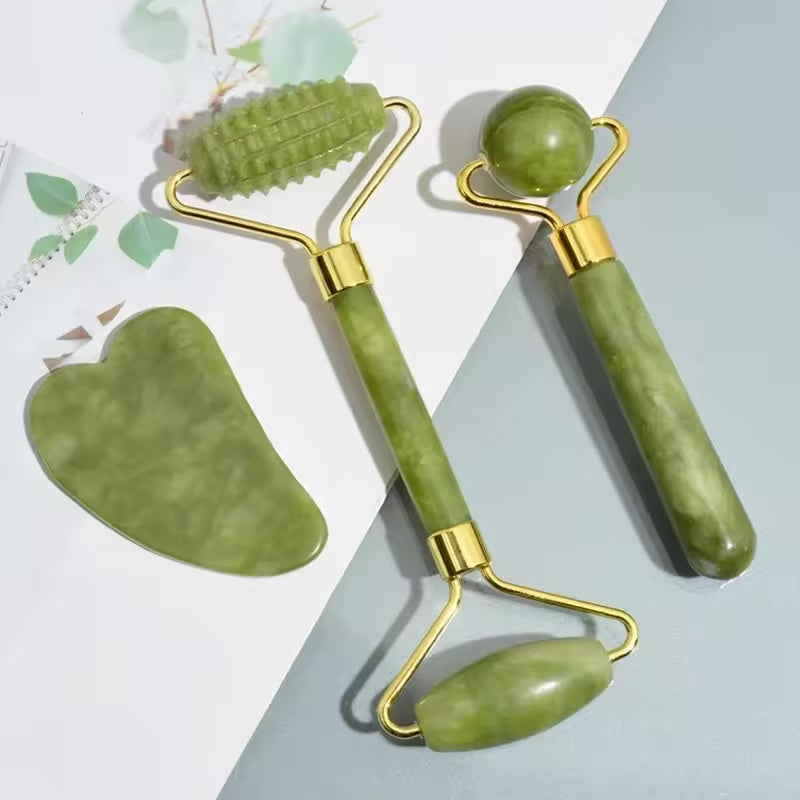 Natural stone roller and gua sha set flat lay with green leaves